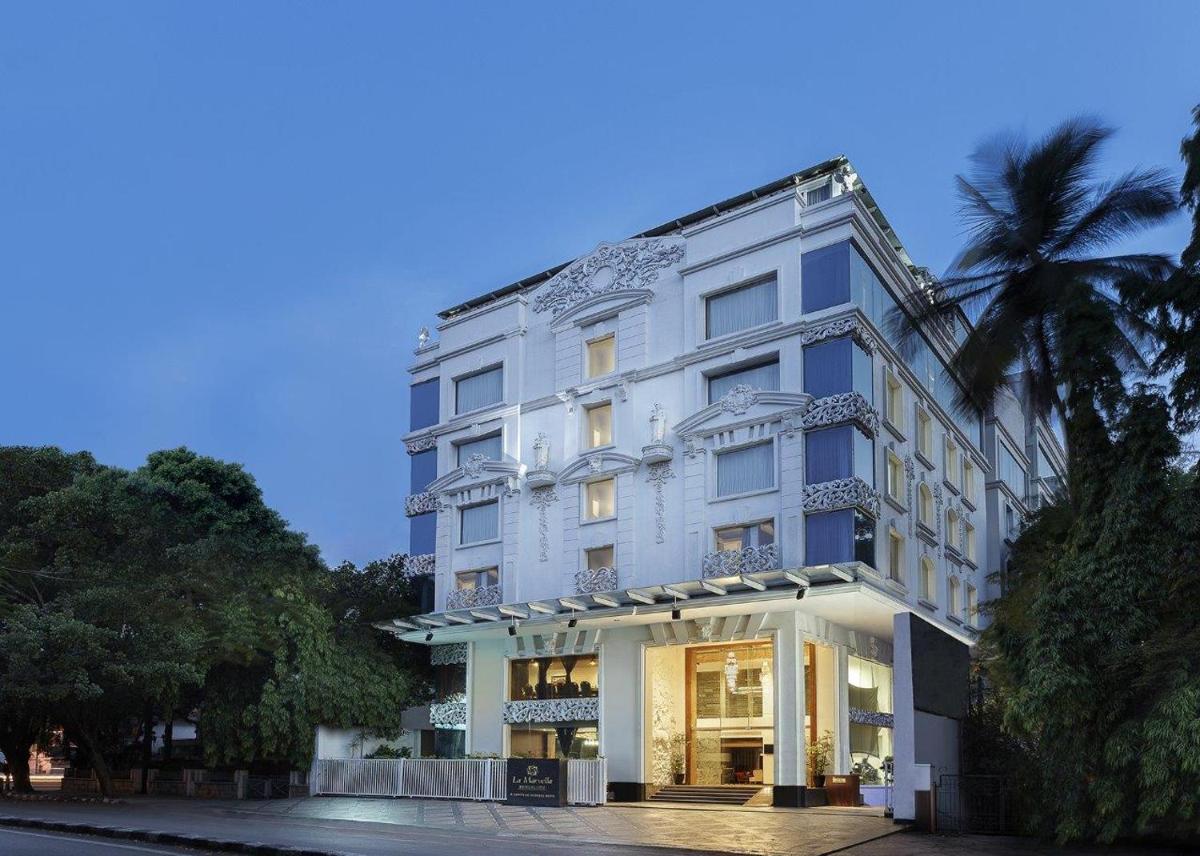 a white building with a palm tree in front of it at La Marvella, Bengaluru in Bengaluru