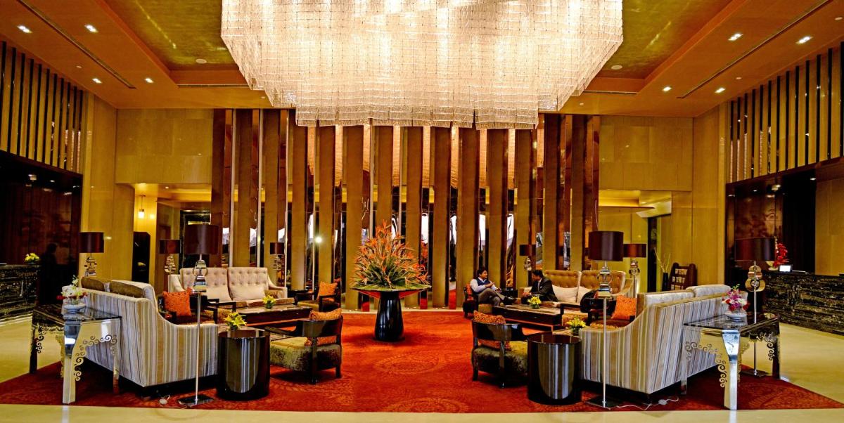 a lobby with chairs and a chandelier in a hotel at Radisson Blu Jaipur in Jaipur