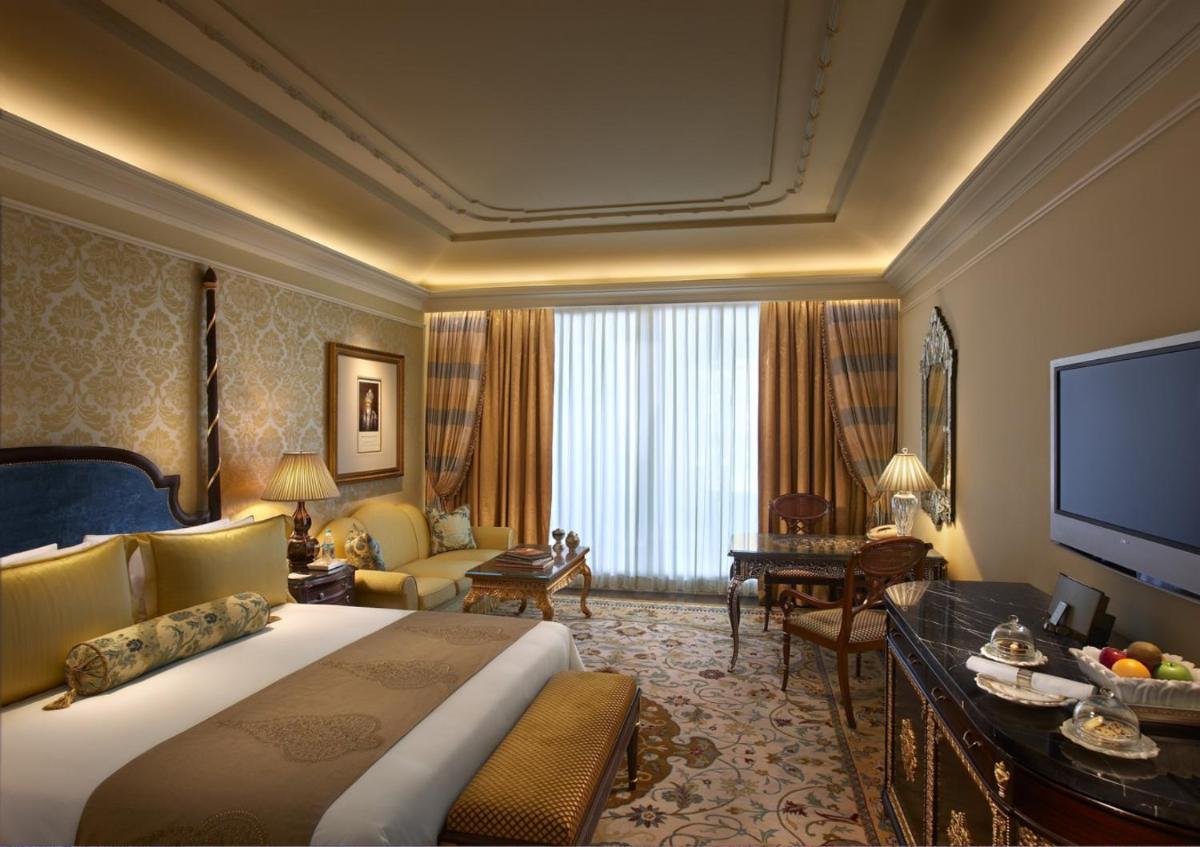 a hotel room with a large bed and a television at The Leela Palace New Delhi in New Delhi a hotel room with a large bed and a television at The Leela Palace New Delhi in New Delhi