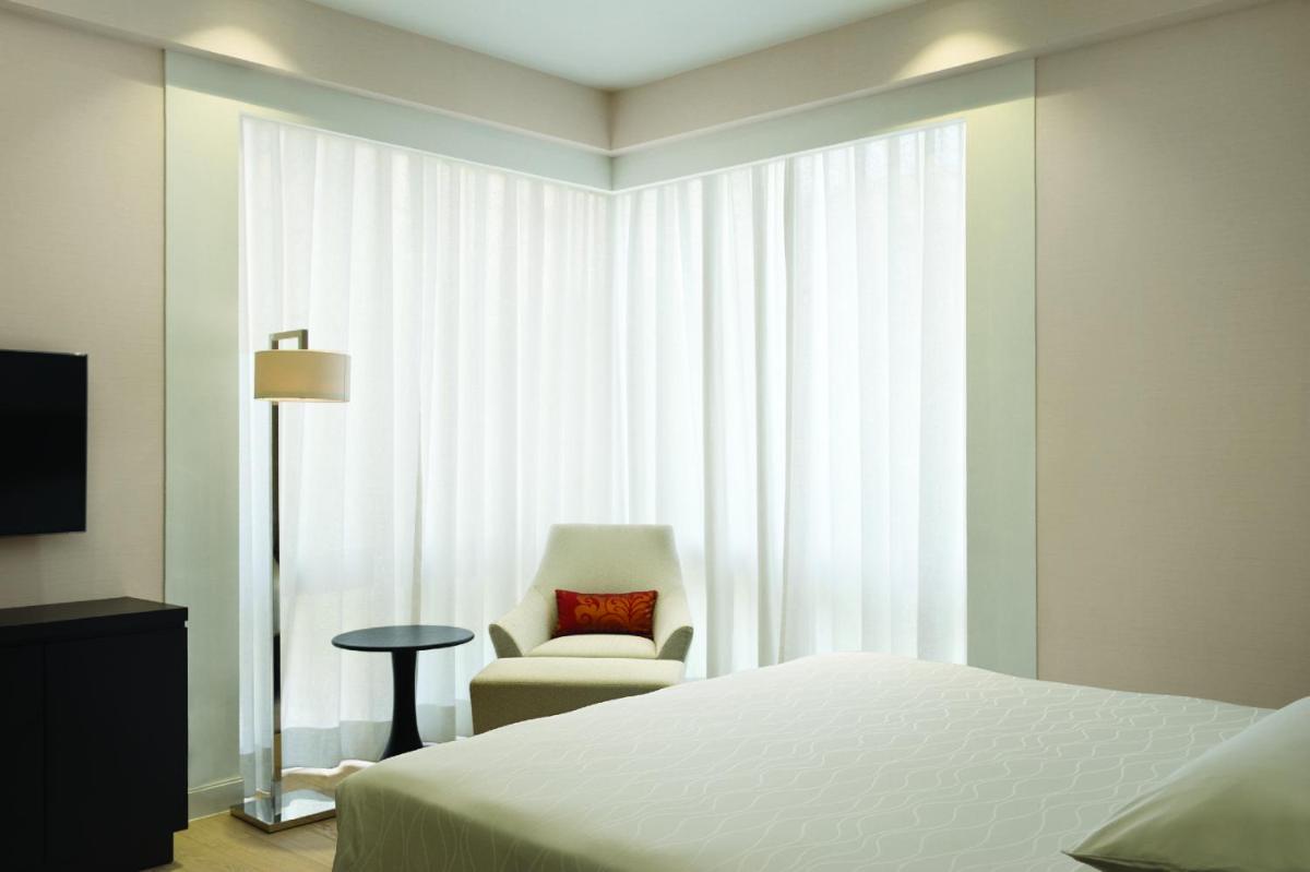 a bedroom with a bed and a chair and a window at Hyatt Regency Delhi in New Delhi a bedroom with a bed and a chair and a window at Hyatt Regency Delhi in New Delhi