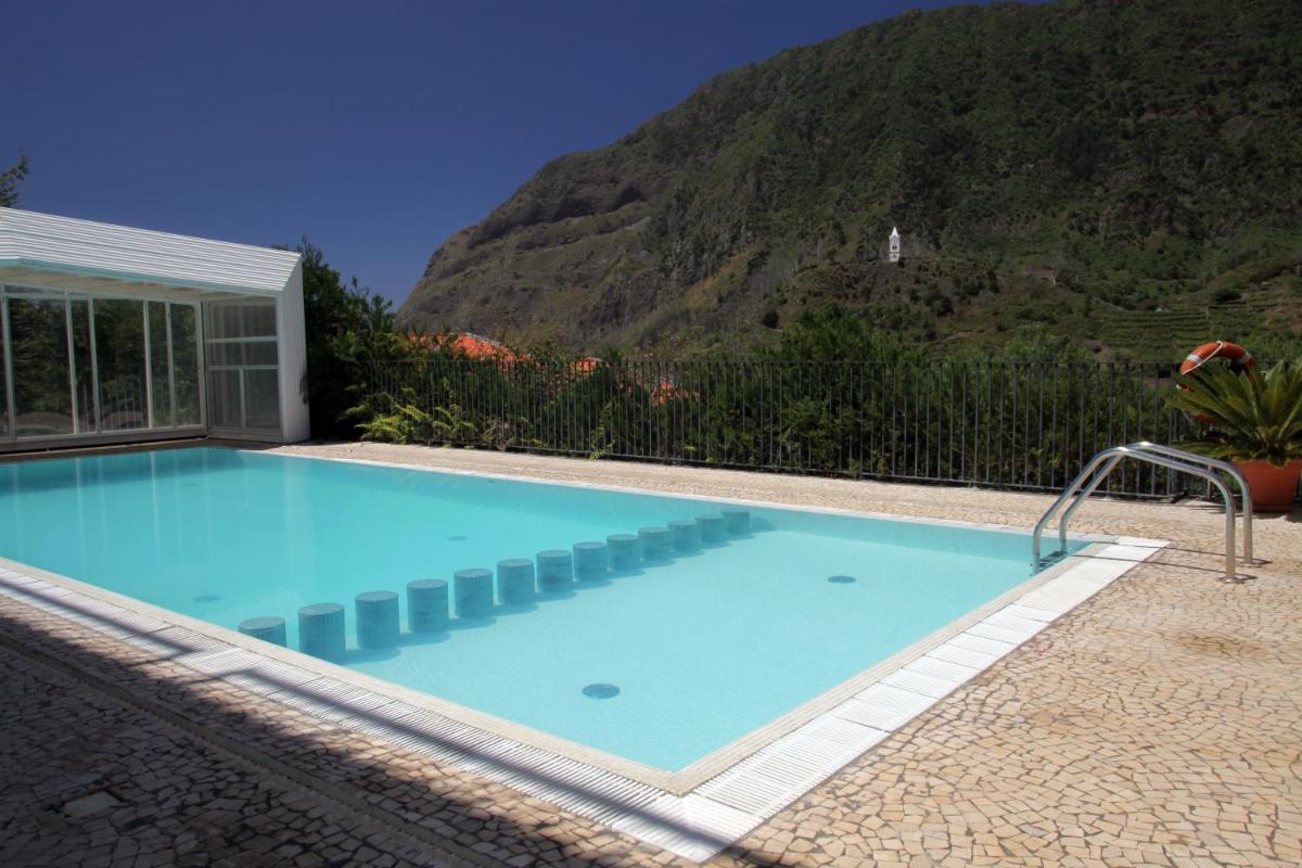uma piscina com uma montanha ao fundo em Estalagem do Vale em São Vicente mais 54 fotografias