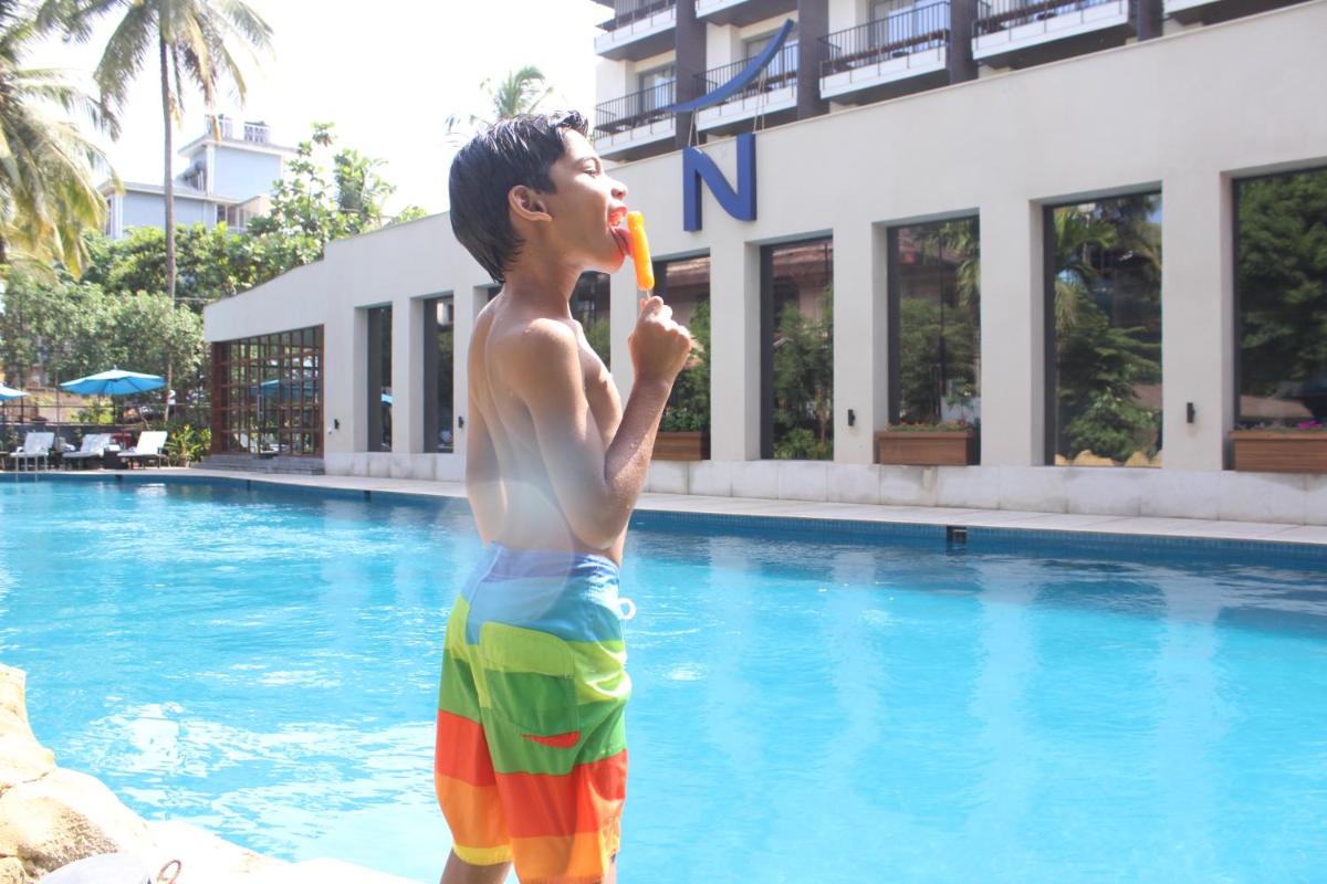 a young boy standing in a swimming pool eating a toy at Novotel Goa Candolim in Candolim a young boy standing in a swimming pool eating a toy at Novotel Goa Candolim in Candolim