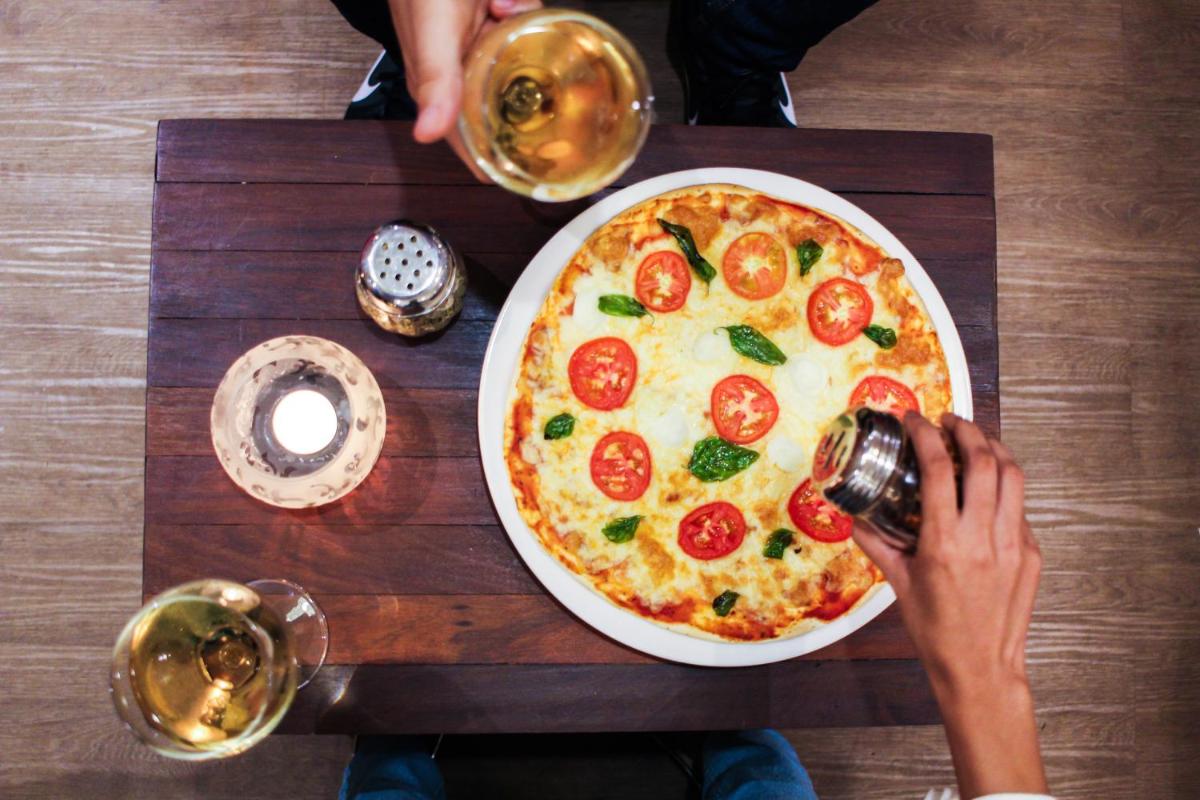 a person taking a picture of a pizza on a table at Novotel Goa Candolim in Candolim a person taking a picture of a pizza on a table at Novotel Goa Candolim in Candolim