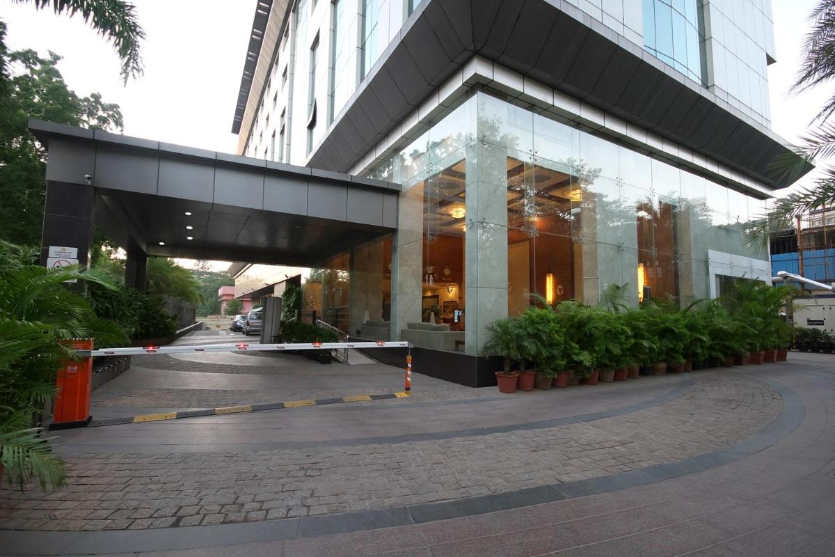 a building with a glass facade with plants in front of it at Fortune Select JP Cosmos, Bengaluru - Member ITC Hotels' Group in Bengaluru