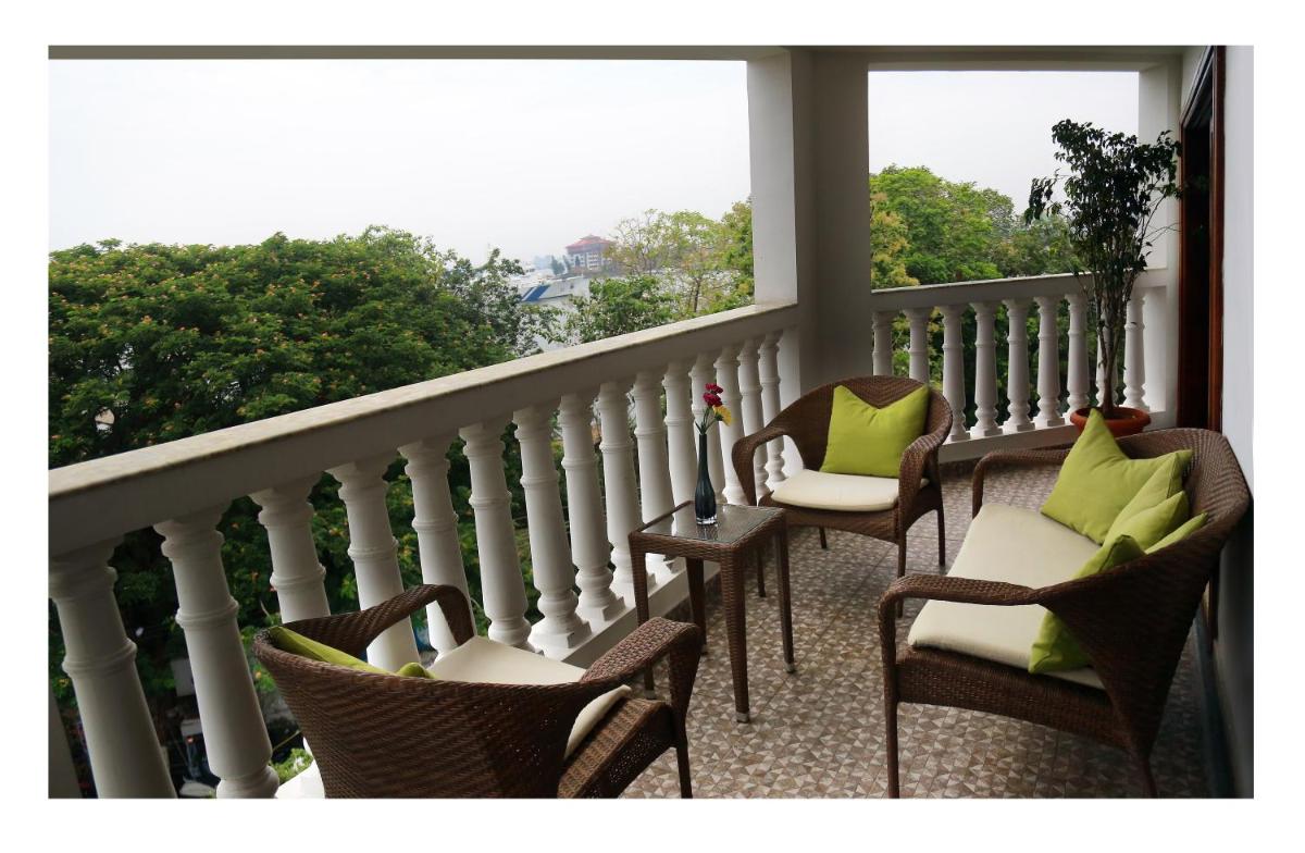 a balcony with chairs with green pillows and a window at Fragrant Nature Kochi - A Five star Classified Hotel in Cochin