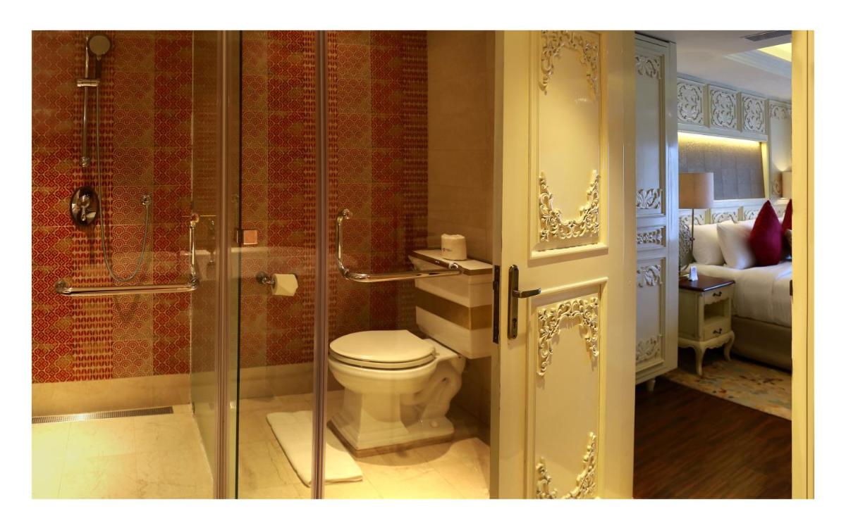 a bathroom with a toilet and a glass shower at Fragrant Nature Kochi - A Five star Classified Hotel in Cochin