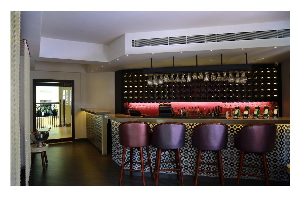 a bar with purple bar stools and wine glasses at Fragrant Nature Kochi - A Five star Classified Hotel in Cochin