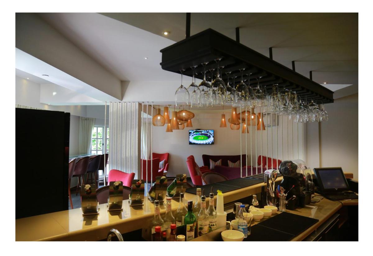 a bar with red chairs and a chandelier at Fragrant Nature Kochi - A Five star Classified Hotel in Cochin