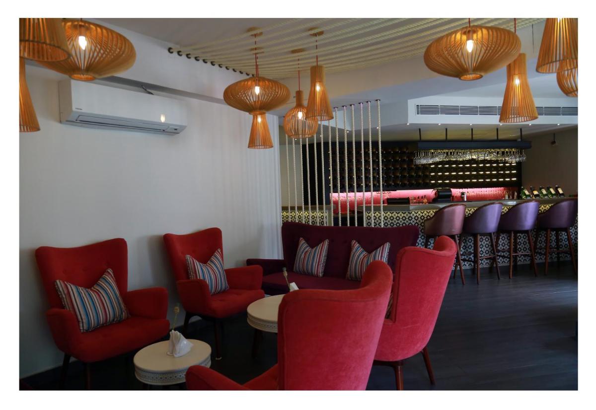 a waiting room with red chairs and a bar at Fragrant Nature Kochi - A Five star Classified Hotel in Cochin