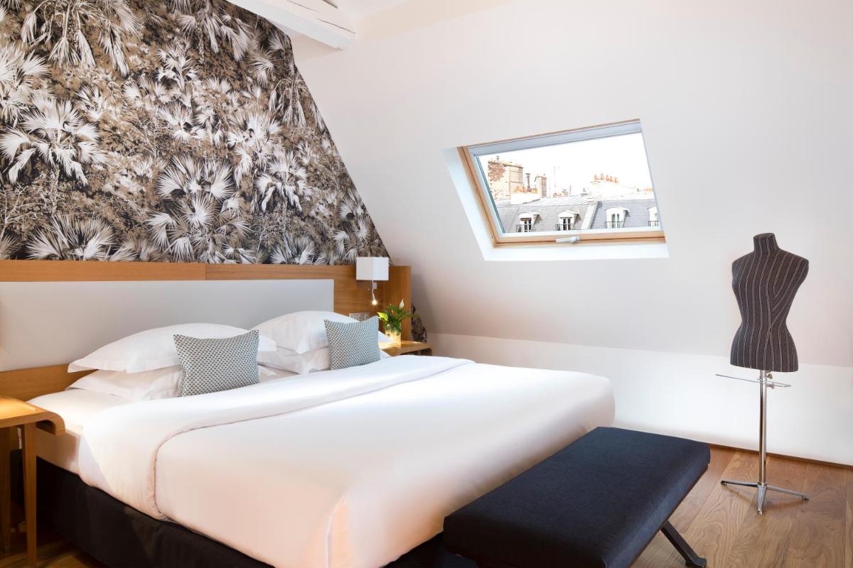 une chambre avec un grand lit blanc et une chaise dans l'établissement Hotel Le Six, à Paris
