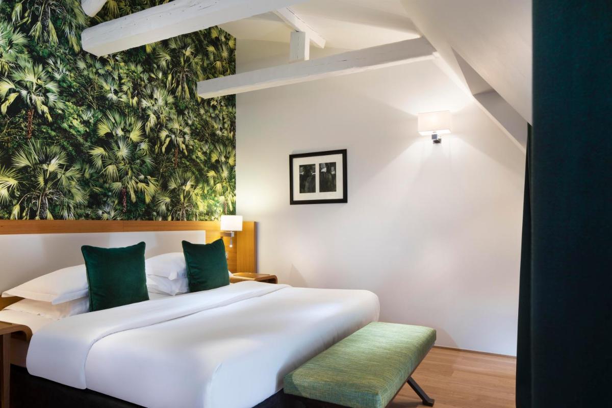 - une chambre avec un grand lit blanc et un banc vert dans l'établissement Hotel Le Six, à Paris