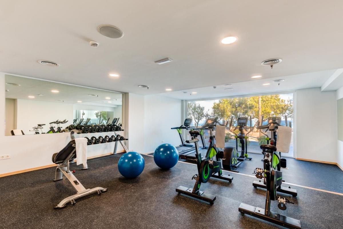 un gimnasio con máquinas de correr y un espejo grande en Talayot - Adults Only, en Cala Millor