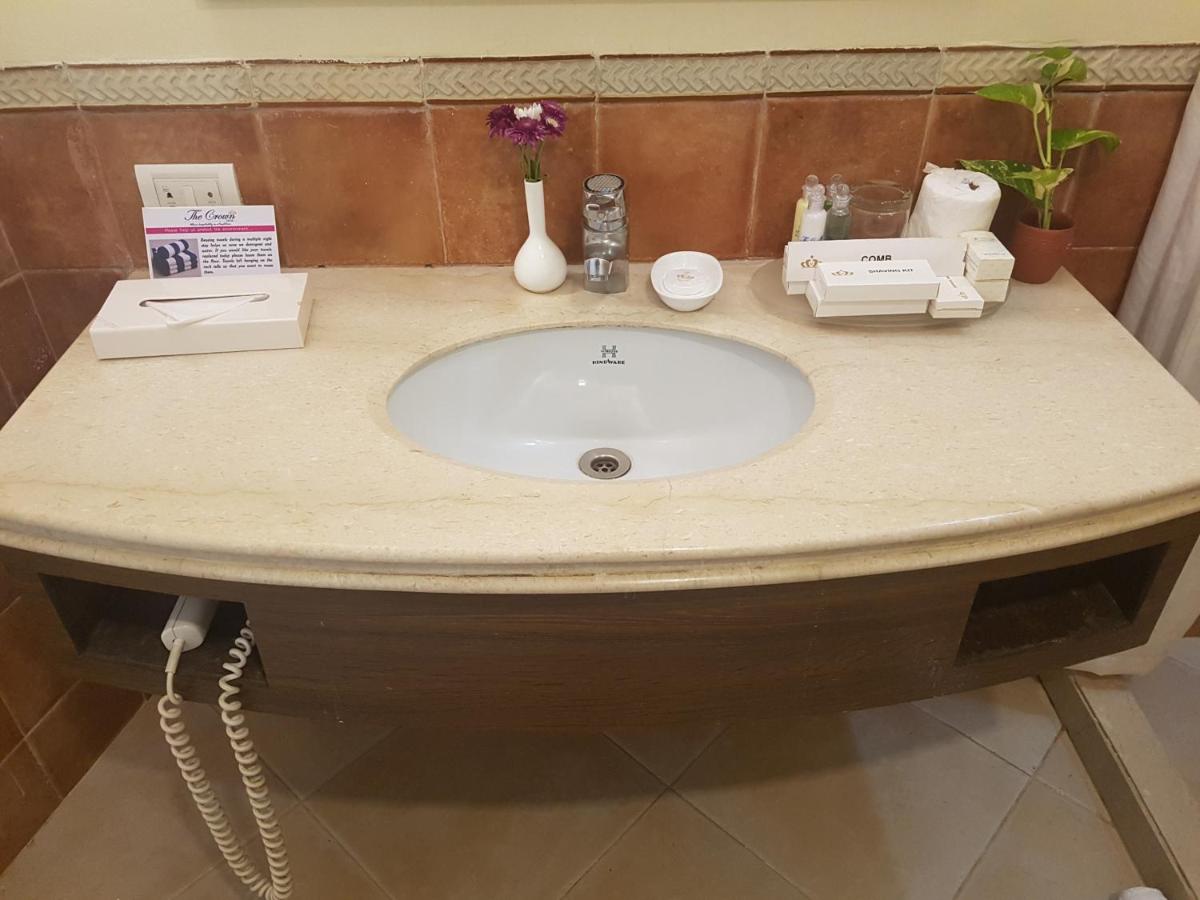 a bathroom counter with a sink with flowers on it at The Crown Goa in Panaji