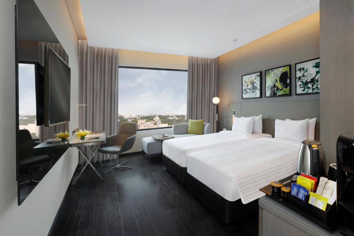 a hotel room with a large bed and a desk at Novotel Chennai Chamiers Road in Chennai