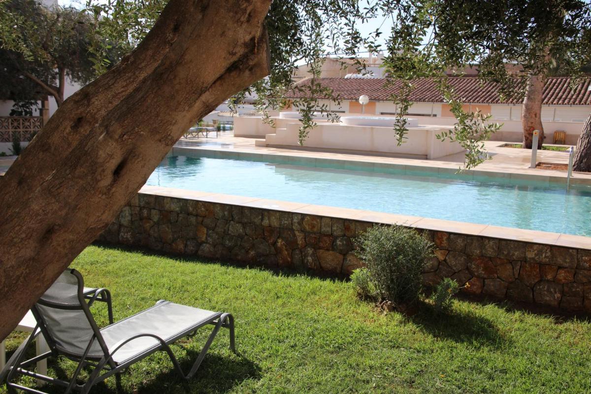 una silla sentada bajo un árbol junto a una piscina en Hotel Clumba, en Cala Ratjada