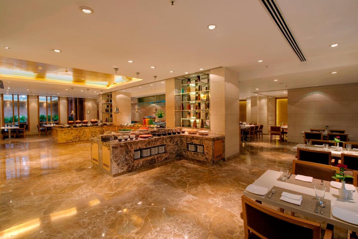 a restaurant with a large lobby with tables and chairs at Jaypee Palace Hotel in Agra