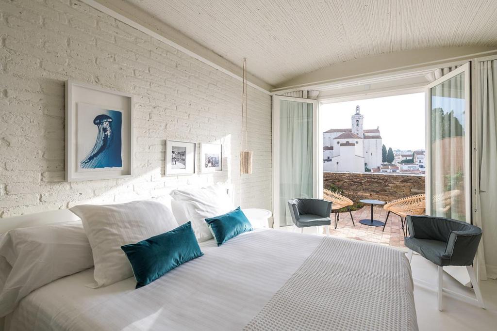 Un dormitorio con una gran cama blanca con almohadas azules. en Boutique Hotel Villa Gala by Fimedhotels, en Cadaqués