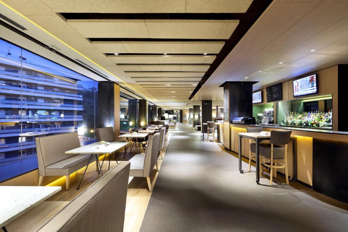 Un restaurante con mesas y sillas y un bar. en Occidental Bilbao, en Bilbao