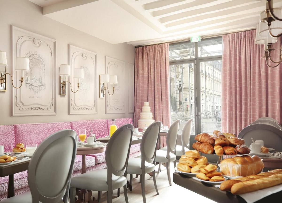 - une salle à manger avec une table, du pain et des viennoiseries dans l'établissement La Maison Favart, à Paris