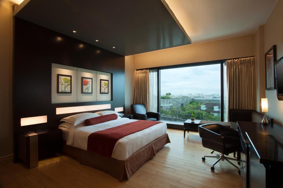 a bedroom with a bed and a desk and a window at The Oterra in Bengaluru