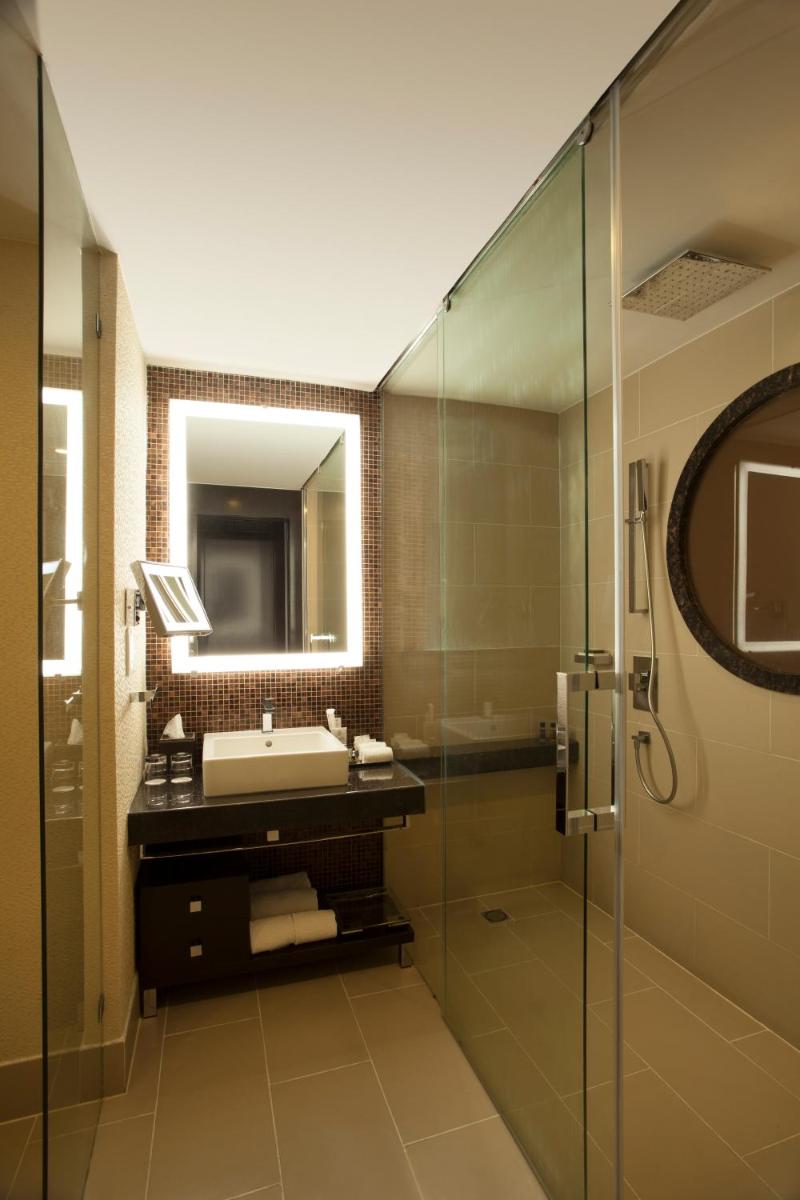 a bathroom with a sink and a glass shower at The Oterra in Bengaluru a bathroom with a sink and a glass shower at The Oterra in Bengaluru