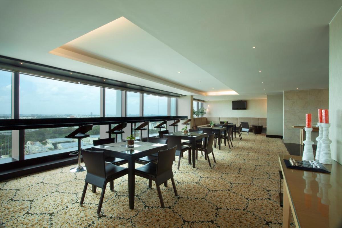 a dining room with tables and chairs and large windows at The Oterra in Bengaluru
