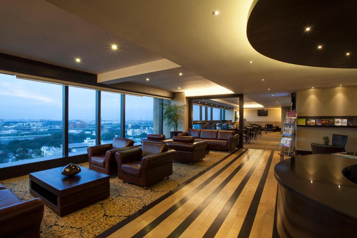 a large living room with couches and chairs and windows at The Oterra in Bengaluru