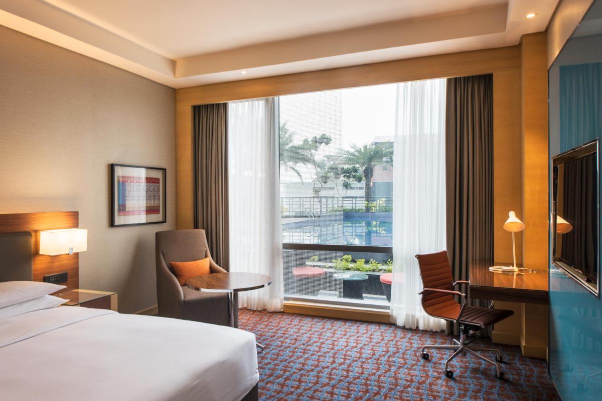 a hotel room with a bed and a desk and a window at Hyatt Regency Lucknow Gomti Nagar in Lucknow