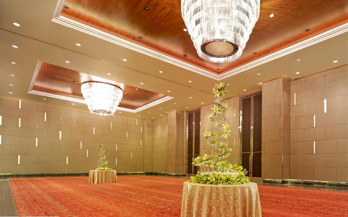 a large lobby with two tables and two plants at Taj City Centre Gurugram in Gurgaon
