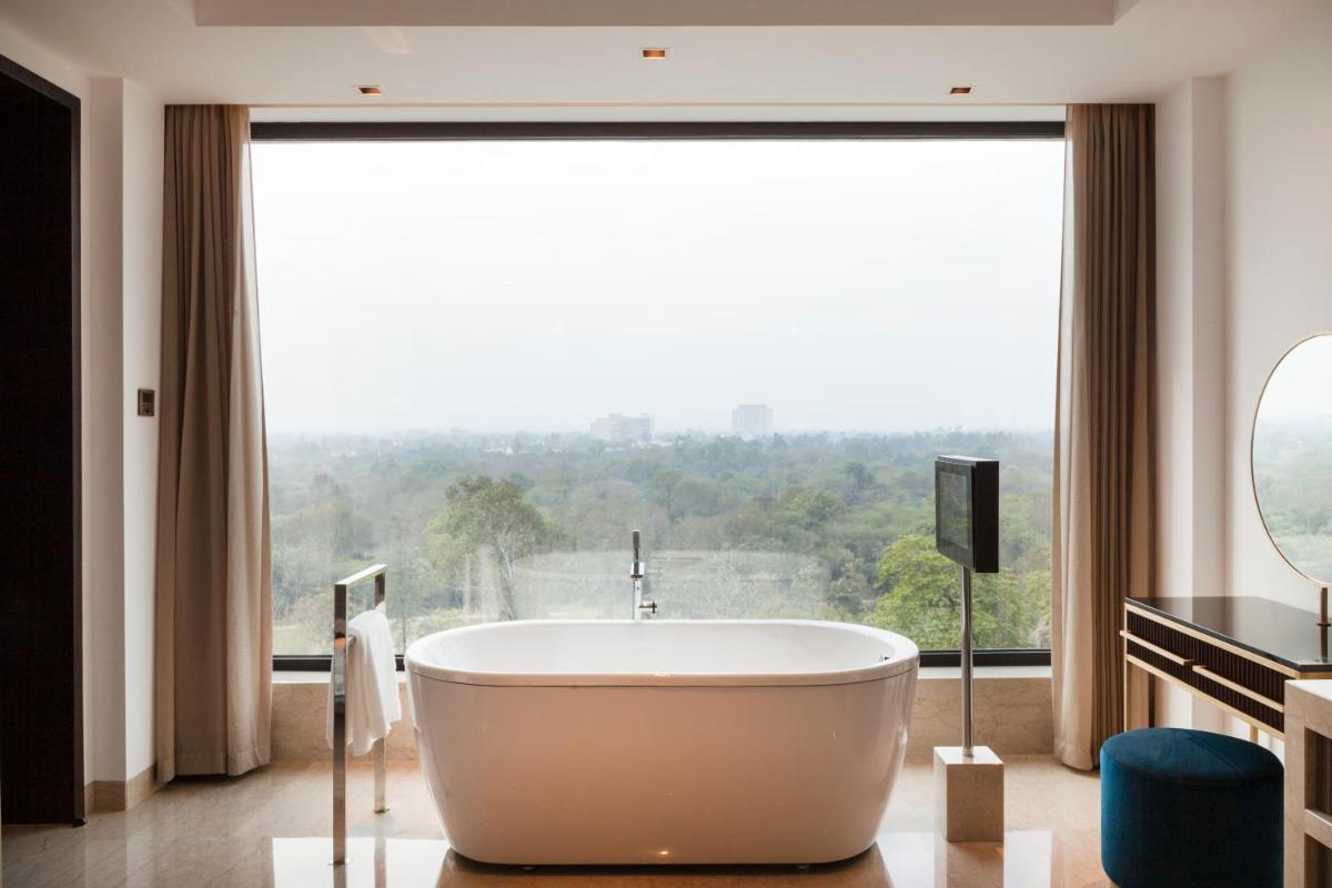 a bath tub in a bathroom with a large window at The Oberoi New Delhi in New Delhi a bath tub in a bathroom with a large window at The Oberoi New Delhi in New Delhi