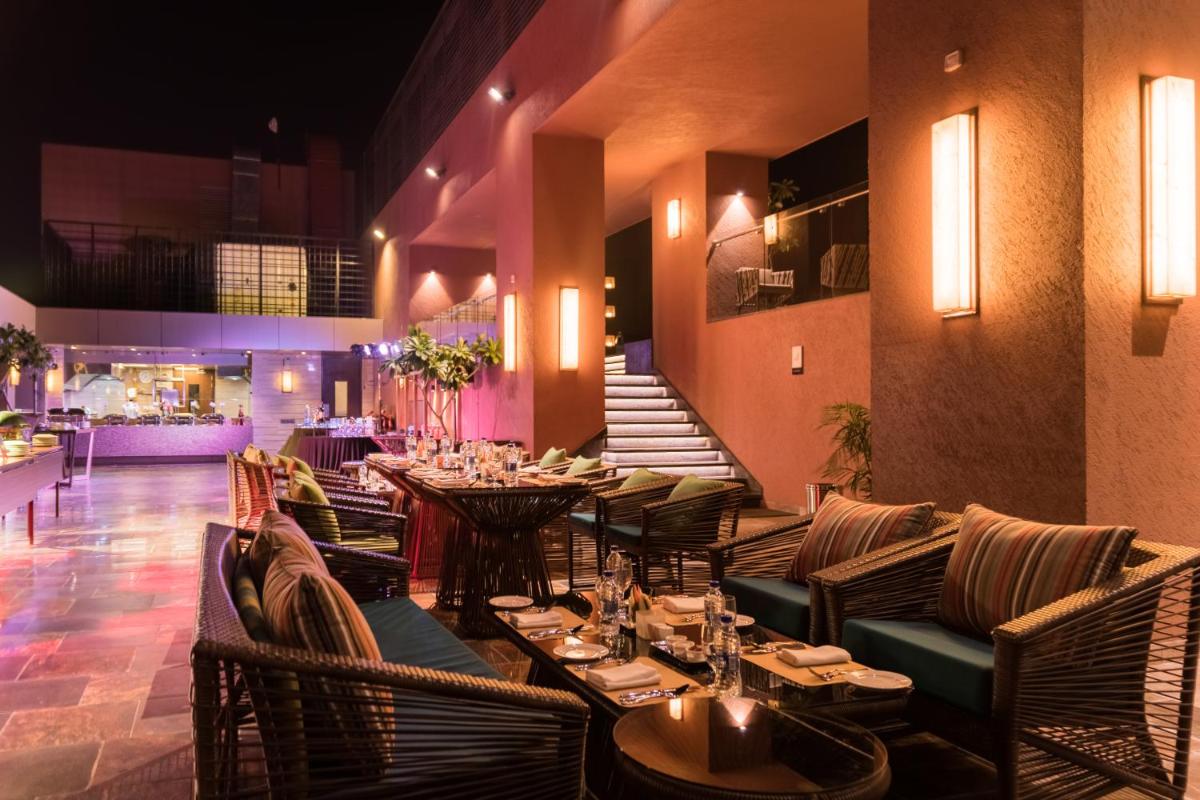 a restaurant with tables and chairs in a room at Novotel Lucknow Gomti Nagar in Lucknow