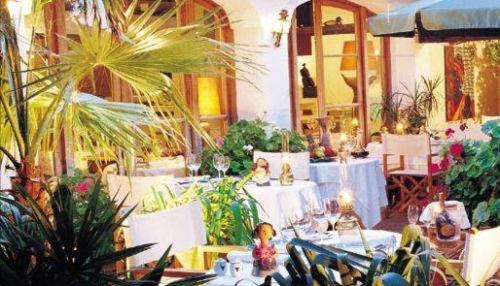 un restaurant avec des tables blanches et des plantes en pot dans l'établissement Mangio Fango Hotel et Spa, à Saintes-Maries-de-la-Mer