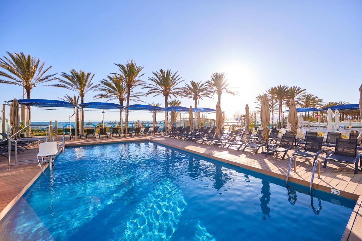 Una gran piscina con sillas y palmeras. en Hotel Negresco - Adults Only, en Playa de Palma