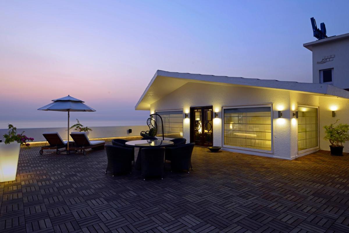 a building with a patio with chairs and an umbrella at Sun-n-Sand Mumbai Juhu Beach in Mumbai