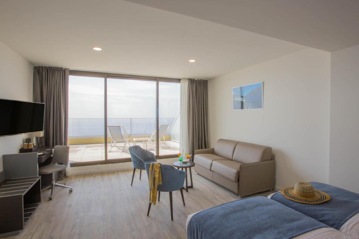 un salon avec un lit, un canapé et un bureau dans l'établissement Les Terrasses d'Eze - Hôtel & Spa, à Èze