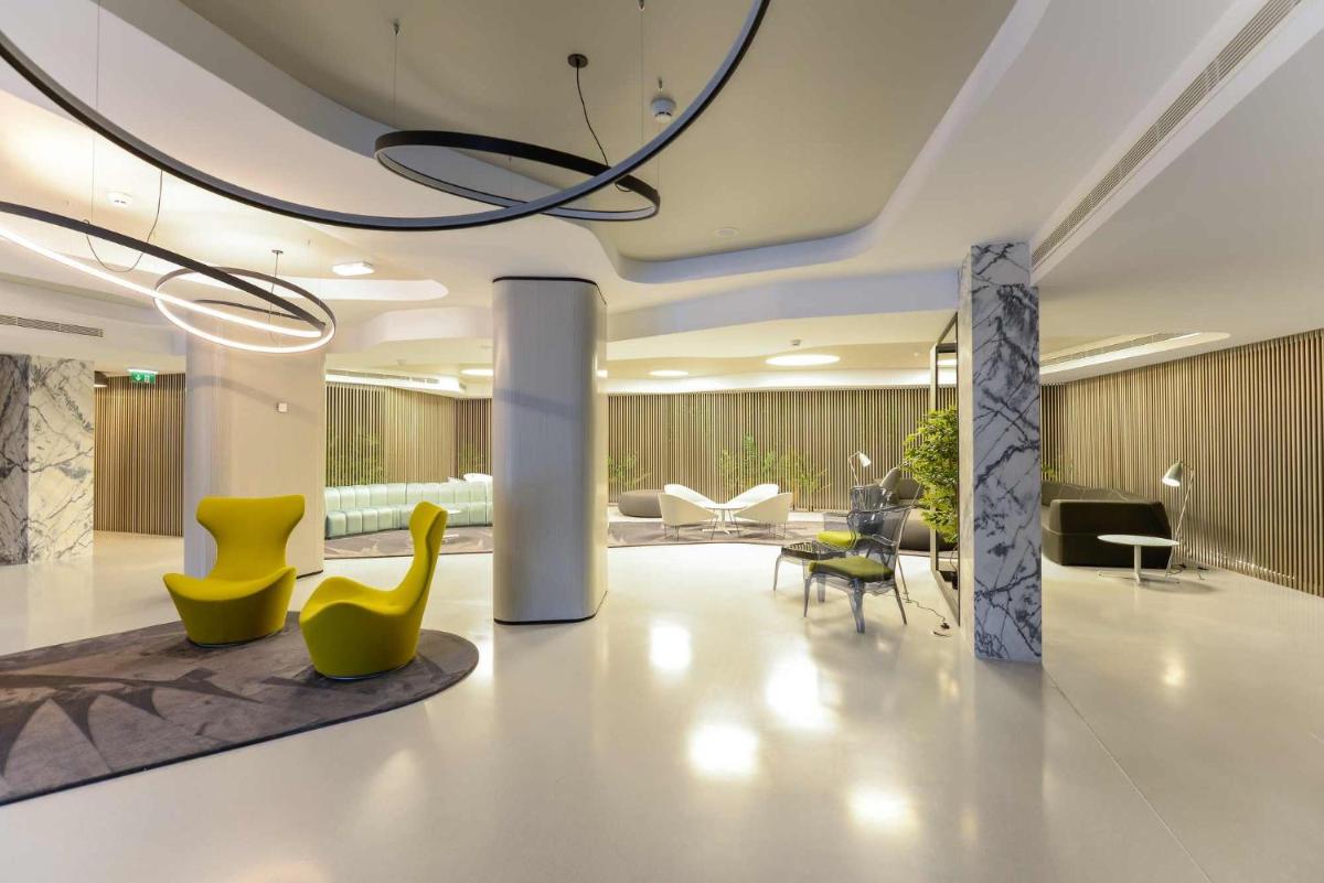 um átrio com cadeiras amarelas e mobiliário num edifício em Azoris Angra Garden – Plaza Hotel em Angra do Heroísmo