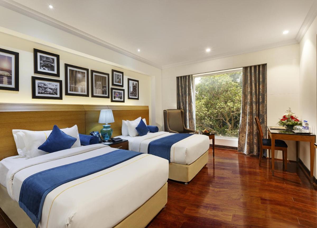 two beds in a hotel room with a window at La Marvella, Bengaluru in Bengaluru