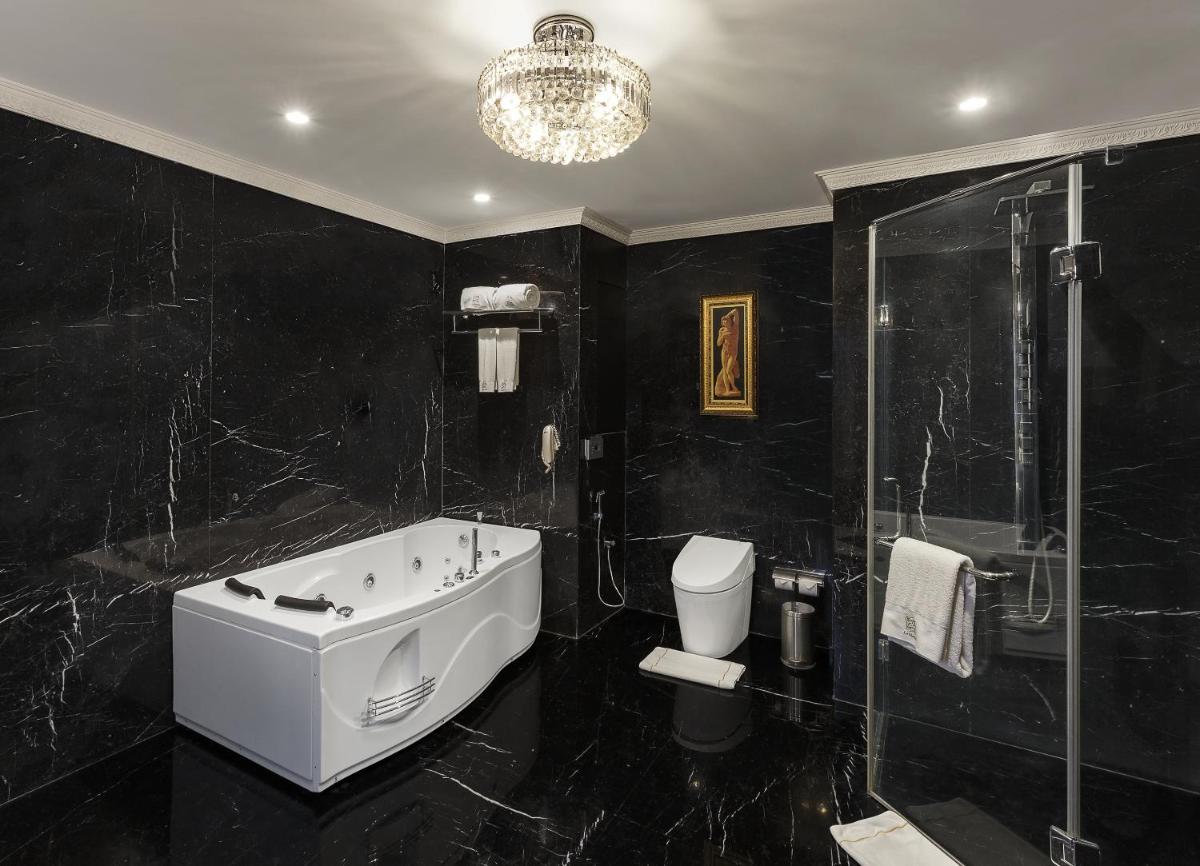 a black bathroom with a tub and a shower at La Marvella, Bengaluru in Bengaluru
