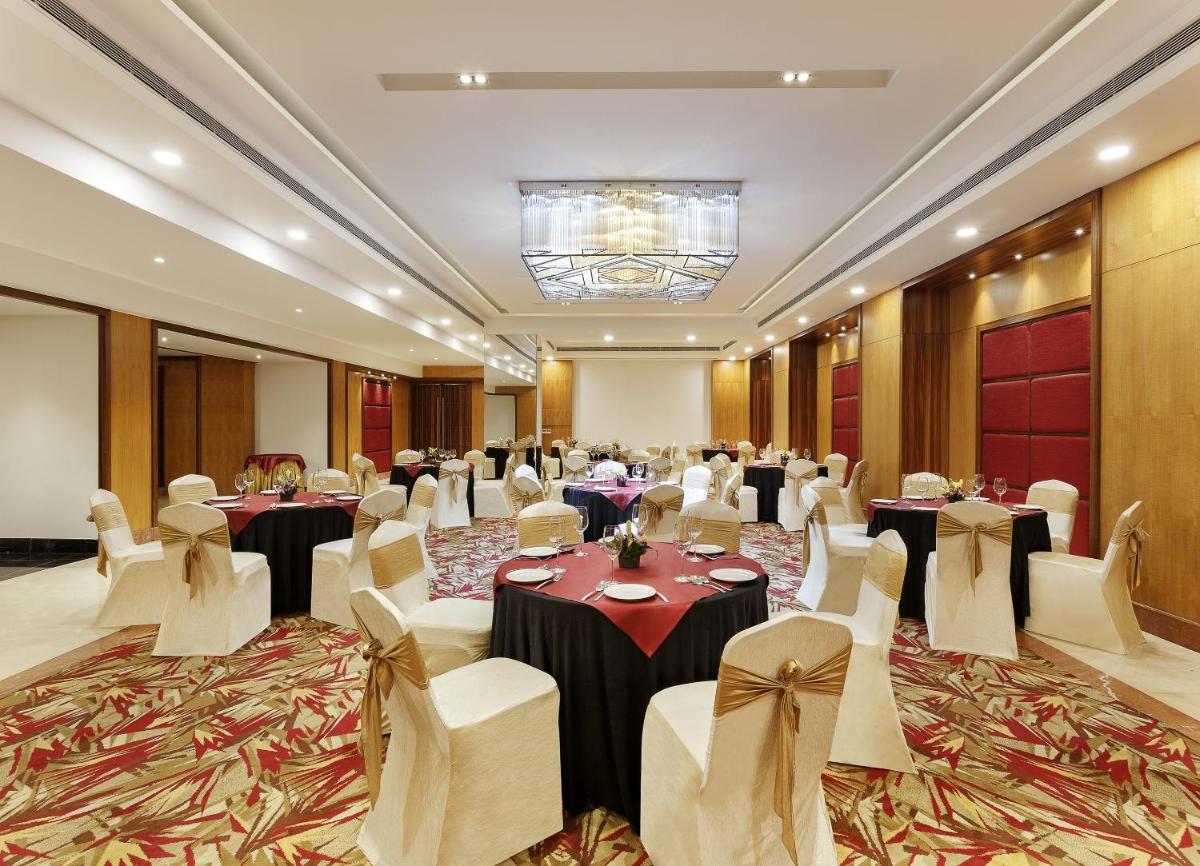 a banquet hall with tables and chairs and a chandelier at La Marvella, Bengaluru in Bengaluru