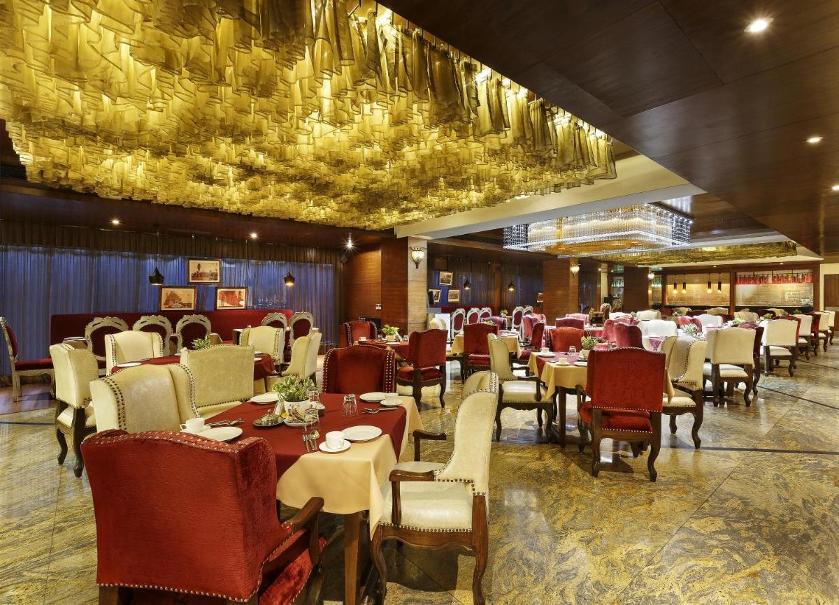 a dining room with tables and chairs and a chandelier at La Marvella, Bengaluru in Bengaluru a dining room with tables and chairs and a chandelier at La Marvella, Bengaluru in Bengaluru