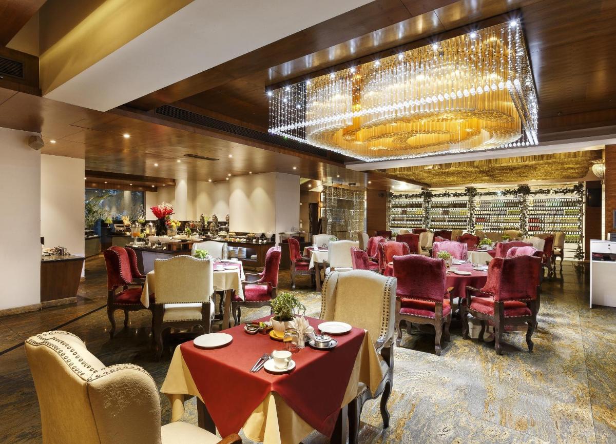 a restaurant with tables and chairs and a chandelier at La Marvella, Bengaluru in Bengaluru