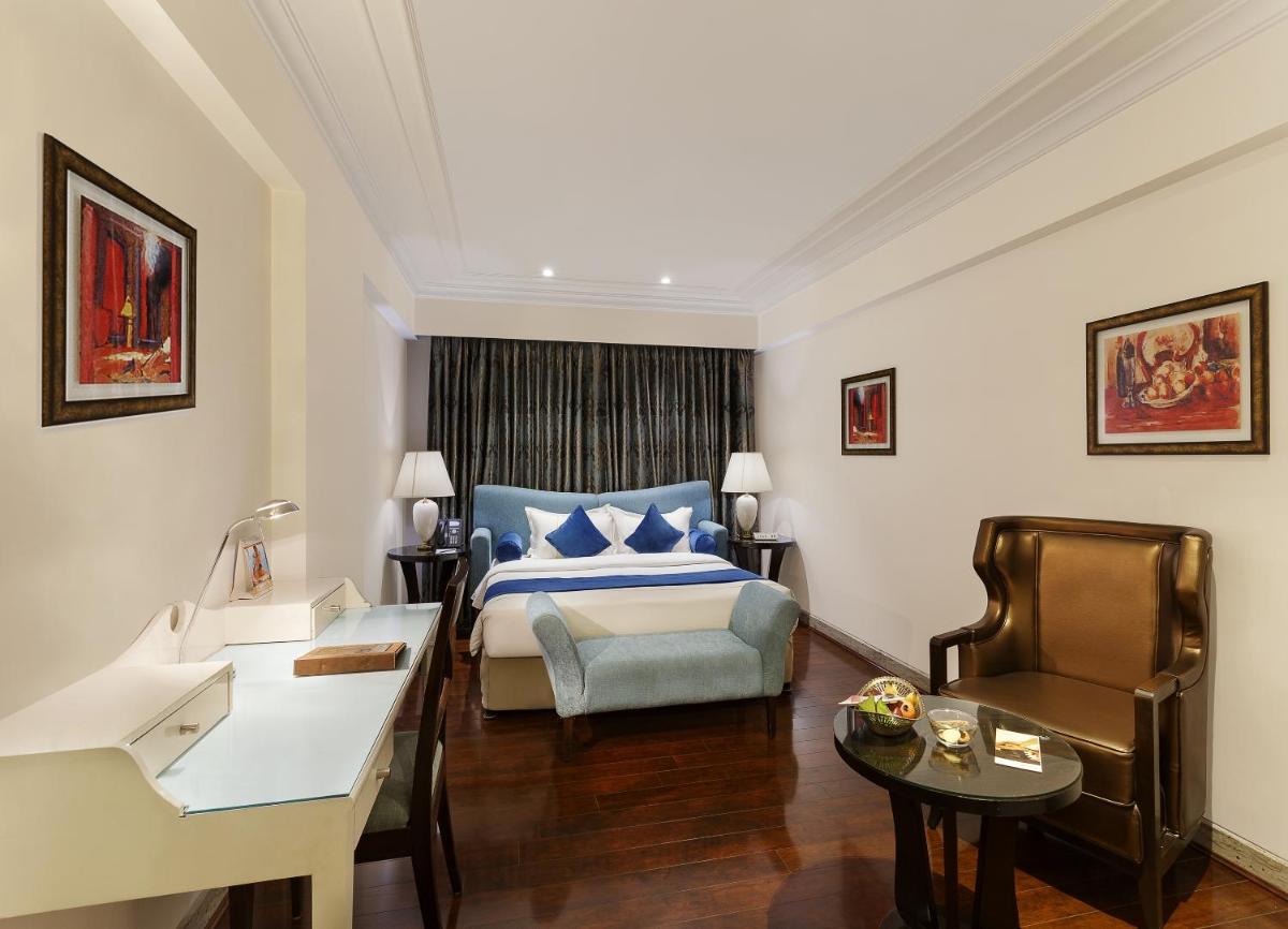 a hotel room with a bed and a desk at La Marvella, Bengaluru in Bengaluru