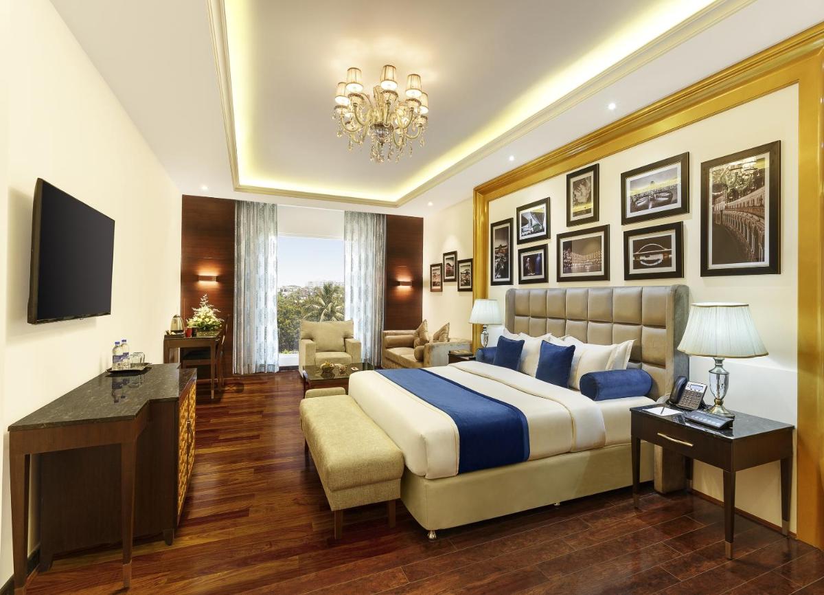 a bedroom with a king sized bed and a desk at La Marvella, Bengaluru in Bengaluru