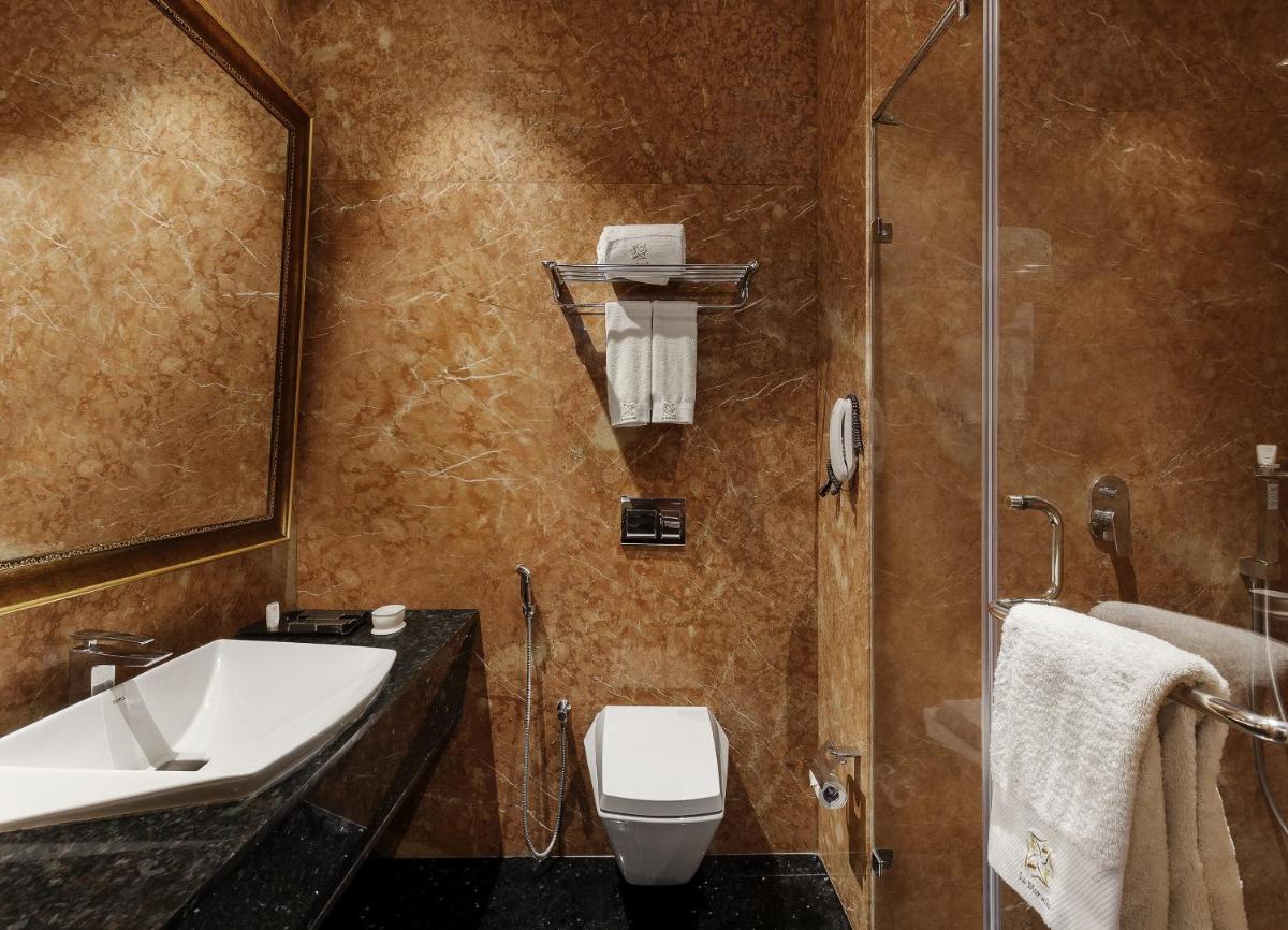a bathroom with a sink and a toilet and a shower at La Marvella, Bengaluru in Bengaluru