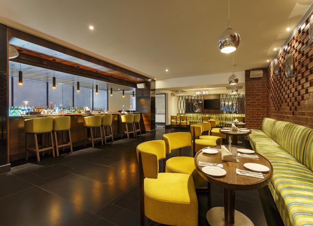 a restaurant with yellow chairs and tables and a bar at La Marvella, Bengaluru in Bengaluru