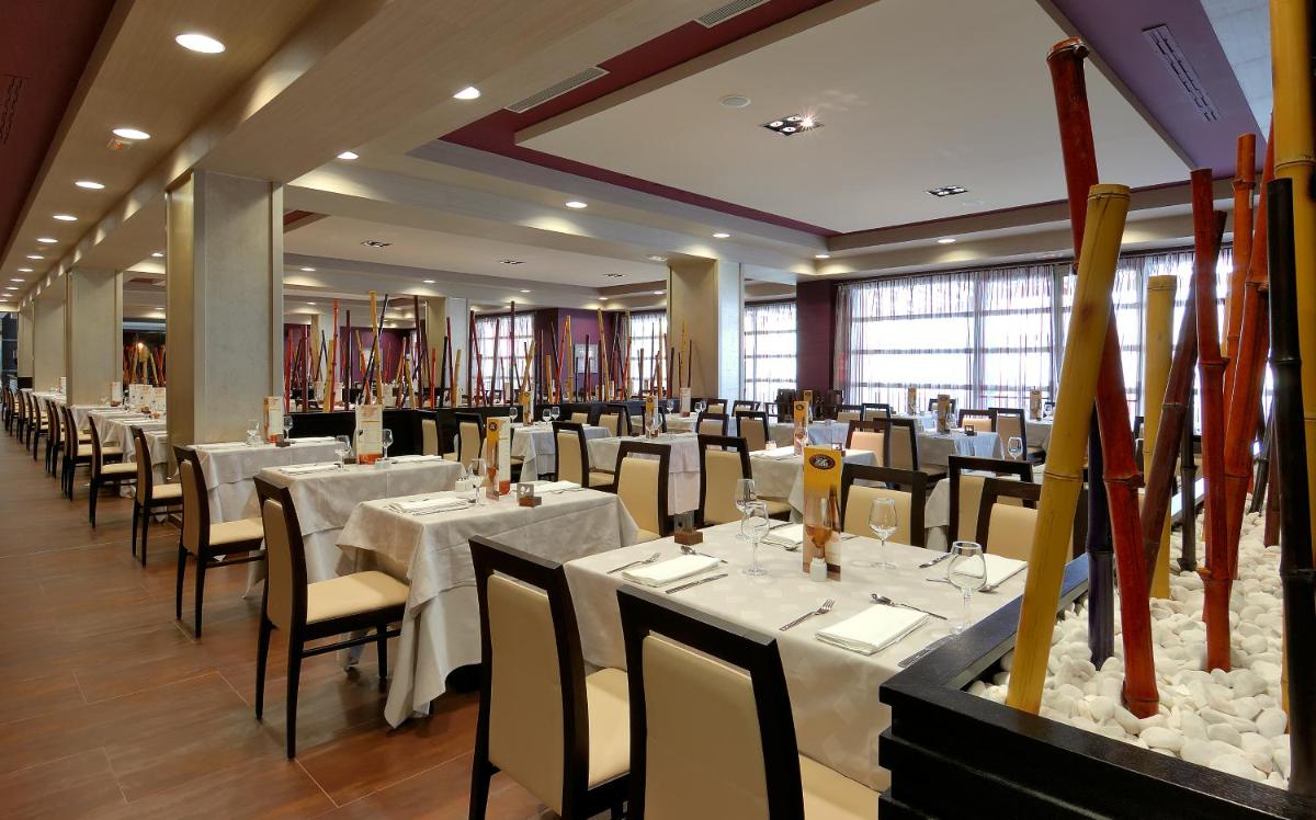 Un comedor con mesas y sillas blancas. en Elba Carlota Beach & Golf Resort, en Caleta de Fuste