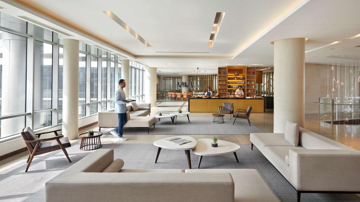 a living room with a person walking in a building at Andaz Delhi, by Hyatt in New Delhi a living room with a person walking in a building at Andaz Delhi, by Hyatt in New Delhi