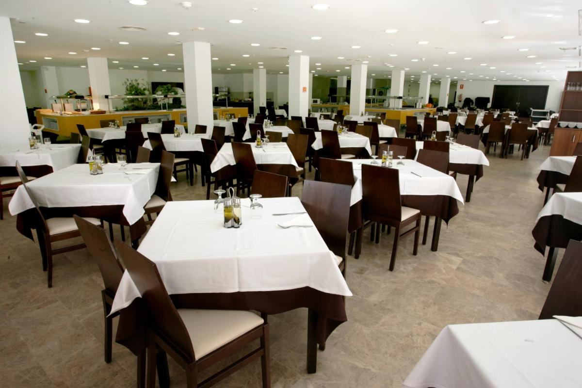 Un comedor con mesas y sillas blancas. en Hotel & SPA Dynastic, en Benidorm