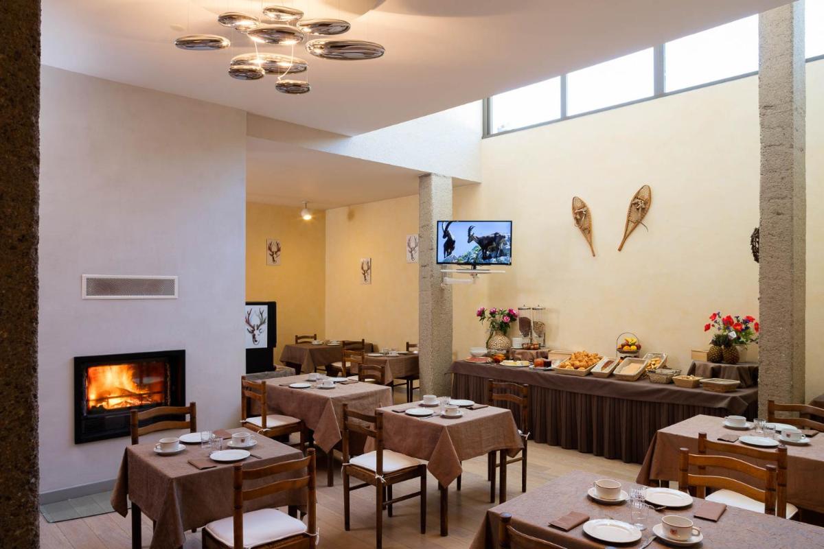 un restaurant avec des tables et des chaises et une cheminée dans l'établissement Hotel le Chalet, à Gresse-en-Vercors