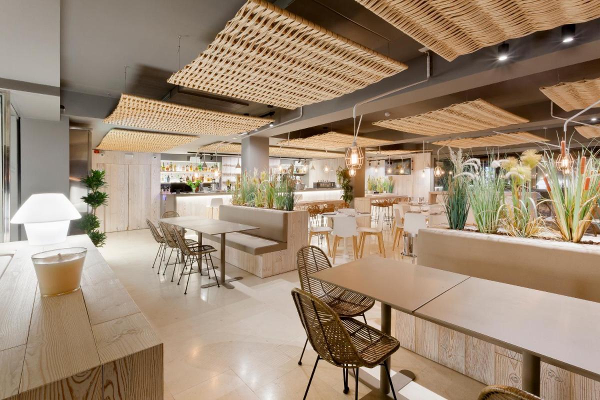 Un restaurante con mesas, sillas y plantas. en Hotel Maritim 4 Superior, en Roses